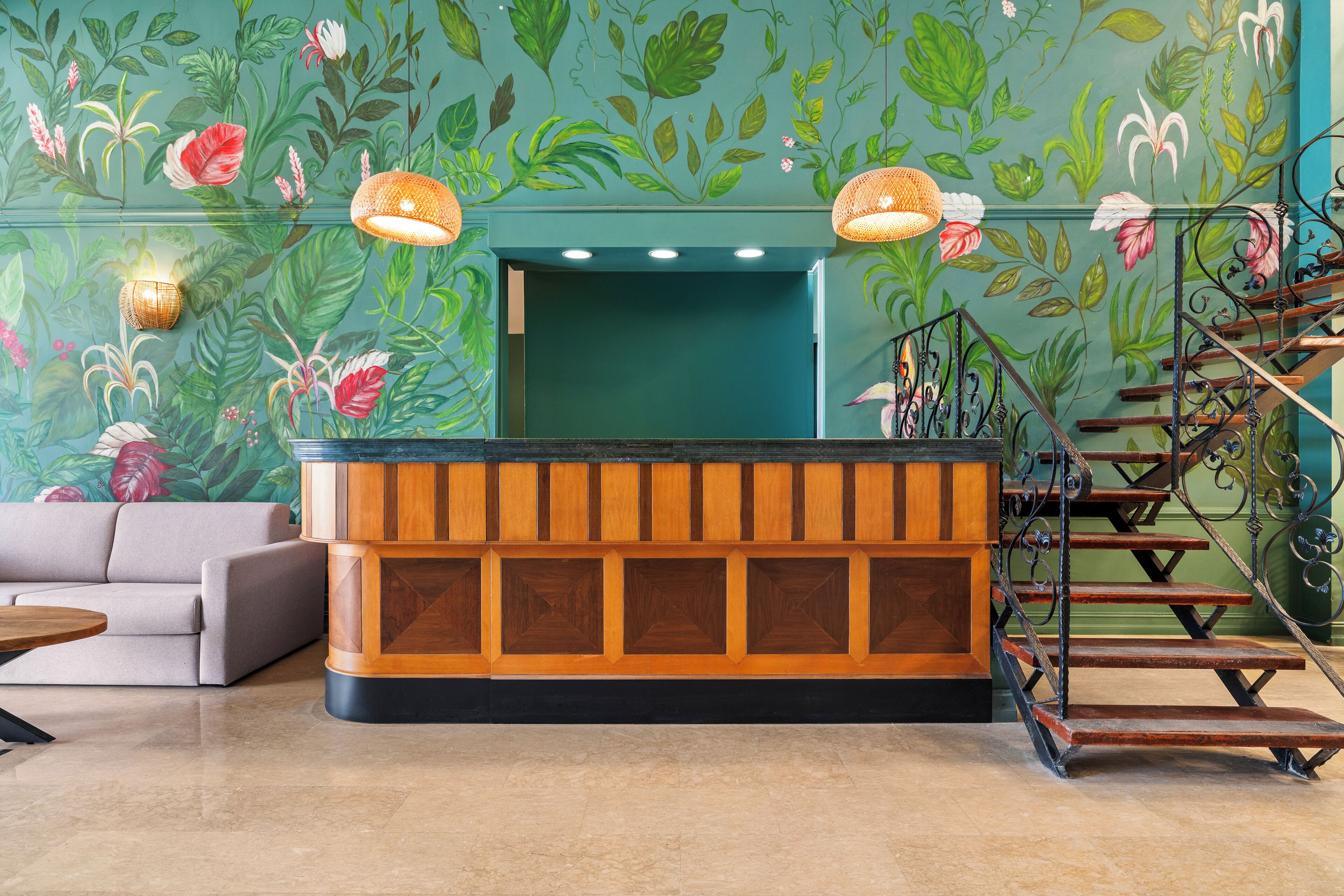 A reception area with a wooden reception desk, a sofa, and a staircase with wrought iron railings.