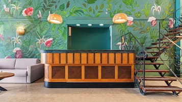 A reception area with a wooden reception desk, a sofa, and a staircase with wrought iron railings.