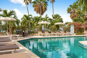 Una piscina al aire libre, sombrillas, sillones reclinables de piscina