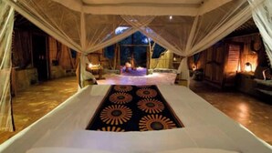 Una habitación con carpa, una cama central, cortinas blancas y vistas al cielo nocturno.