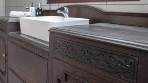 A bathroom with a white sink, dark wooden vanity, and a mirror with a gold frame. - Lake Villa Room 15 (Swartberg)
