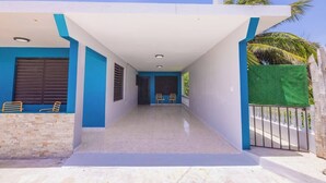 A corridor with a white ceiling, blue walls, and a tiled floor. There are two wooden chairs and a bench along the corridor. - Cozy Studio Type Apartment across Jobos Beach, Isabela. WIFI & A/C. (Isabela)