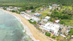 An aerial view of a coastal area with buildings, a beach, and a road. - Cozy Studio Type Apartment across Jobos Beach, Isabela. WIFI & A/C. (Isabela)