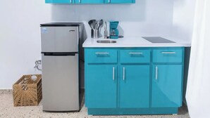 A compact kitchen with teal cabinets, a stainless steel refrigerator, and a coffee maker on the countertop. - Cozy Studio Type Apartment across Jobos Beach, Isabela. WIFI & A/C. (Isabela)