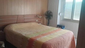 A bedroom with a bed, wooden headboard, a fan, and a window with blinds. - Apartment in fair area (Albacete)