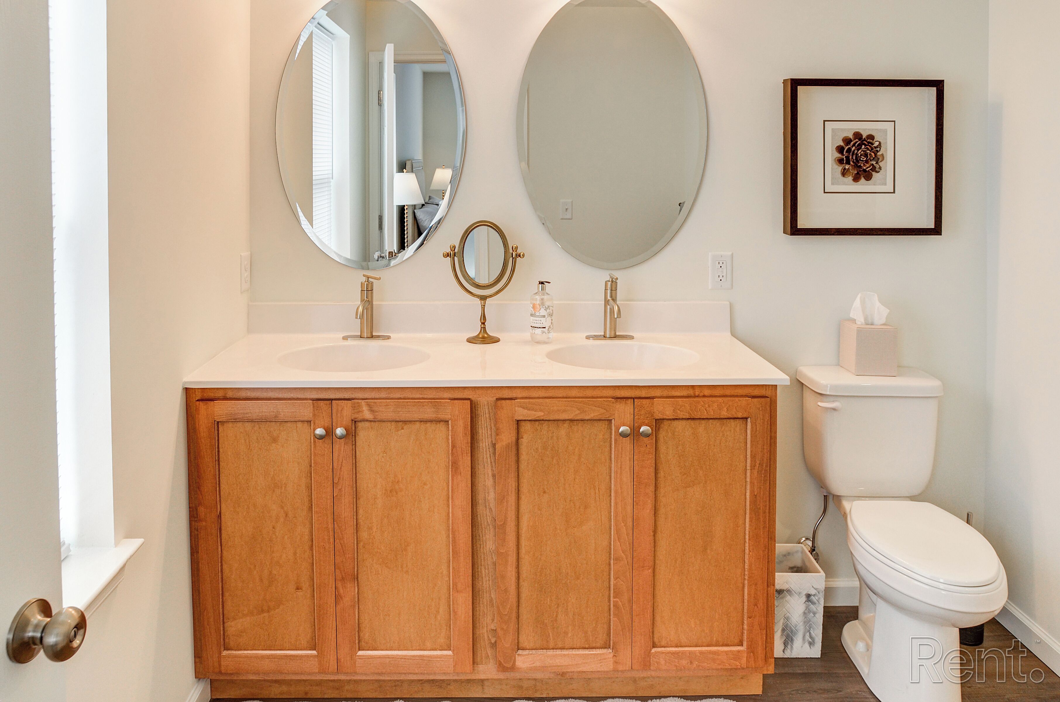 A bathroom with two sinks, a toilet, and wooden cabinets.