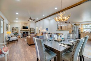 A spacious dining area with a long table, upholstered chairs, and a chandelier.