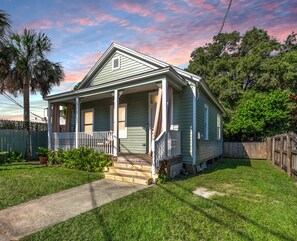 A single-story house with a front porch, a small front yard, and a wooden fence.