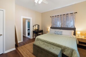 A bedroom with a bed, bedside tables, a desk, and a chair.