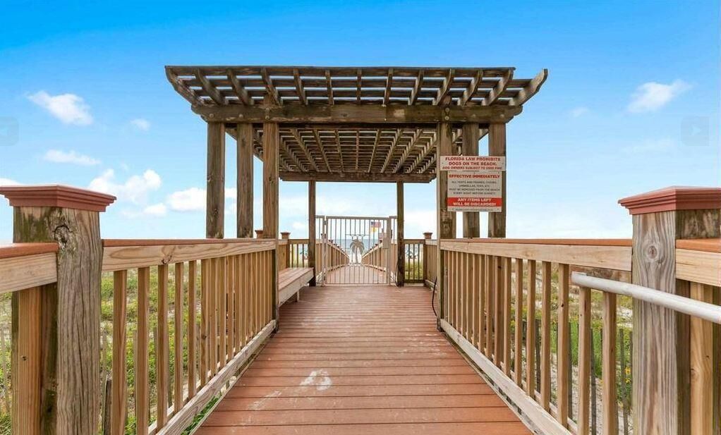 A wooden boardwalk leading to a covered area with a sign.