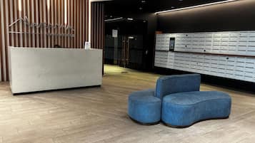 A reception area with a modern design, featuring a reception desk, a set of mailboxes, and a seating area.