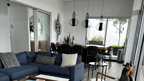 Una sala moderna con un sofá, una mesa de centro y sillas de madera.