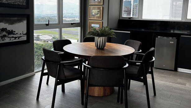 Un comedor moderno con una mesa redonda, seis sillas y una planta en maceta.