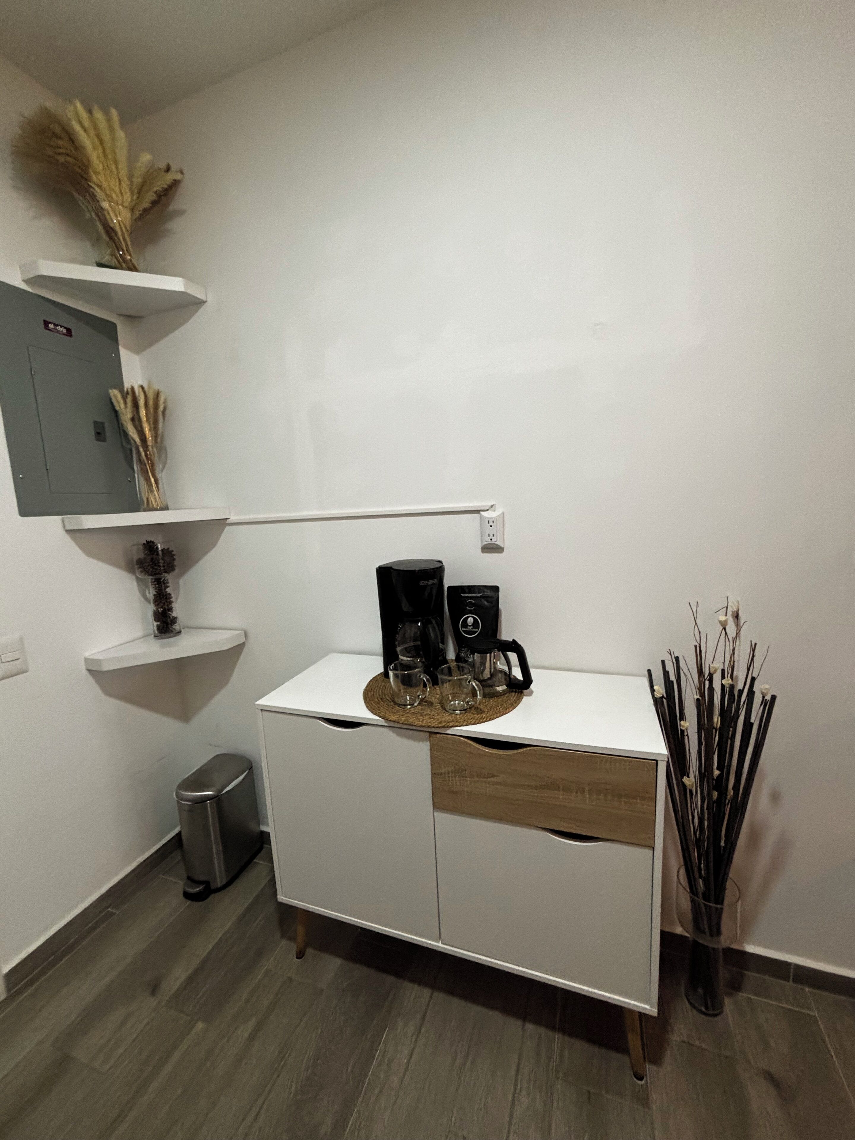 Una cucina moderna con mobili bianchi, una macchina da caffè e un cestino.