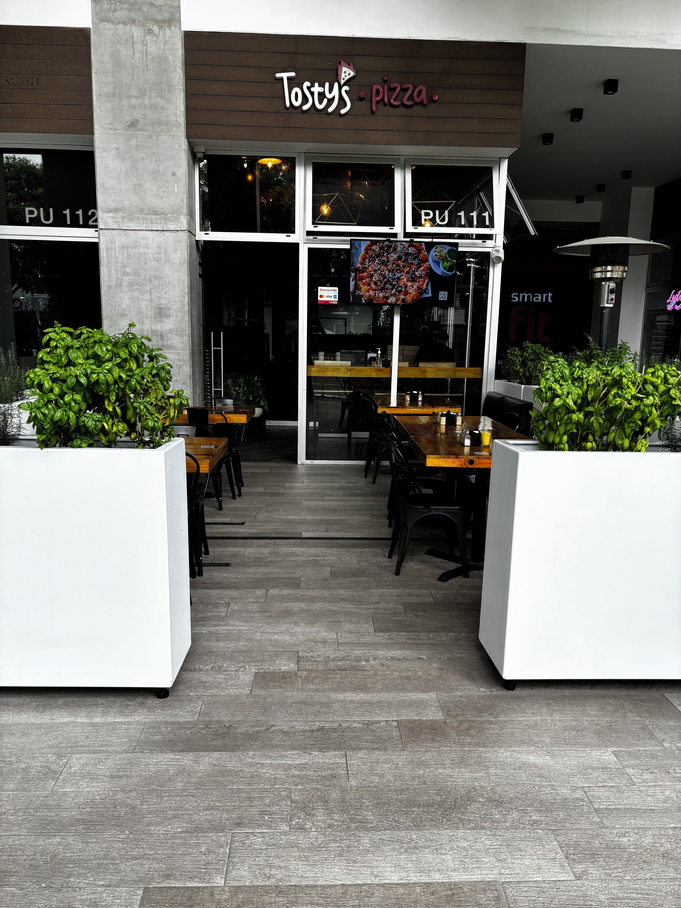 A restaurant named Tostys Pizza with outdoor seating and a modern design.