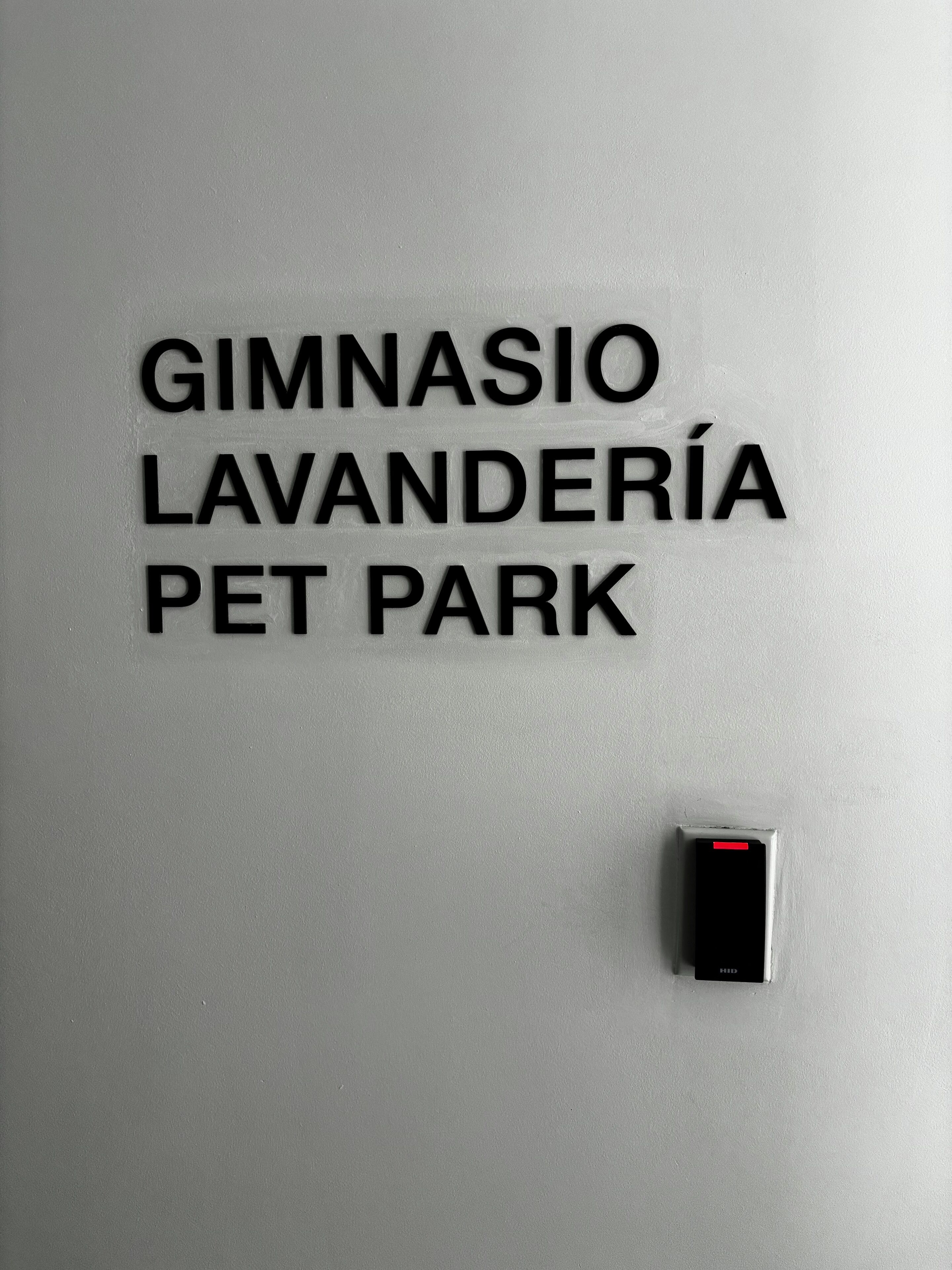 A wall with the text "GIMNASIO LAVANDERÍA PET PARK" and a security device below it.