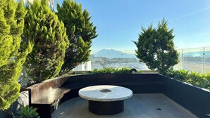 Terraza en la azotea con mesa redonda, zona de estar y plantas en macetas.