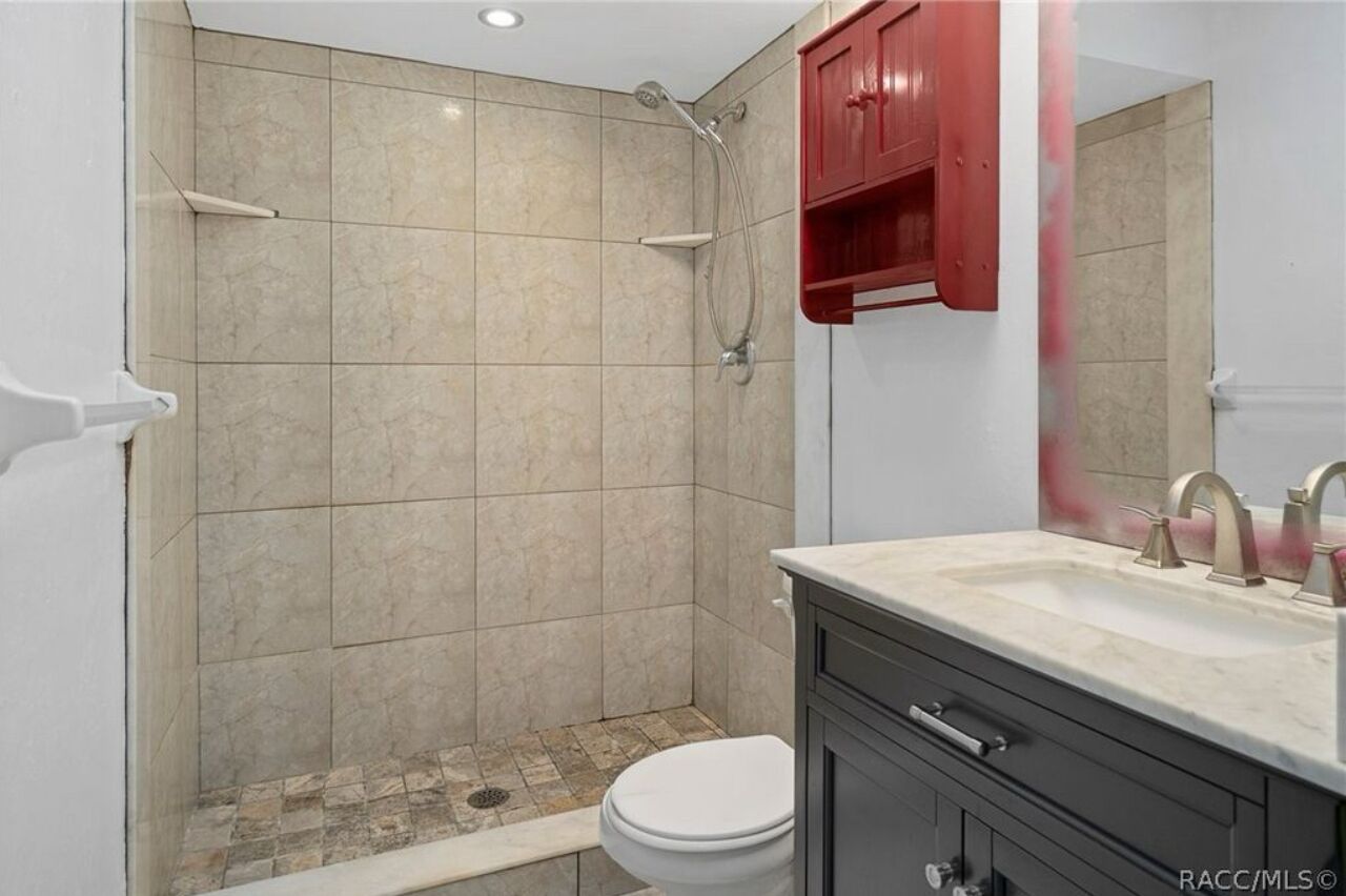 A bathroom with a shower, toilet, and vanity with a sink.