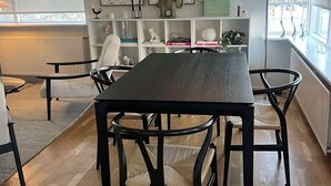 Ein Essbereich mit einem dunklen Holztisch und Stühlen, einer Hängeleuchte und einem Bücherregal mit diversen Gegenständen.