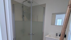 Une salle de bain moderne avec une douche à parois de verre, des toilettes et un meuble-lavabo avec un miroir.