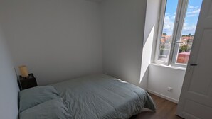 A bedroom with a bed, a nightstand, a window, and a door.