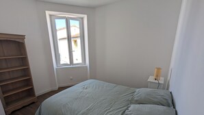 Une chambre à coucher avec un lit, une fenêtre, une armoire en bois et une lampe de chevet.