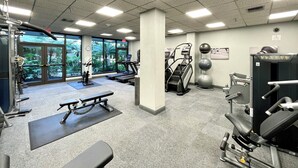 Une salle de sport équipée de tapis de course, d’appareils de musculation et de ballons d’exercice.