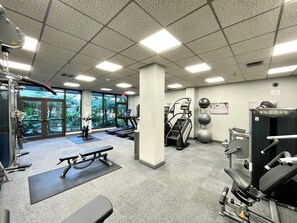 A gym with exercise equipment, a treadmill, and a bench.