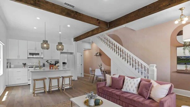 A spacious living area with a kitchen, a staircase, and a modern sofa. - 4BR (Sleeps 10!)Heart of Little Italy: Walk to Dining & Fun! (San Diego)