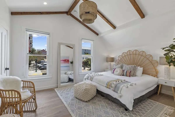 Un dormitorio con una cama grande, dos ventanas, un ventilador de techo y vistas al exterior.