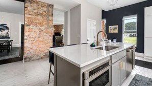 Una cocina moderna con una isla grande, electrodomésticos de acero inoxidable y una pared decorativa de ladrillo.