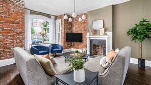 Una sala de estar con pared de ladrillo, chimenea y un ventanal grande.