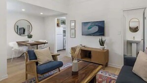 Ein modernes Wohnzimmer mit einer Couch, einem Couchtisch und einem an der Wand befestigten Fernseher.