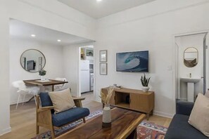 Una sala moderna con sofá, una mesa de centro y un comedor con mesa y sillas.