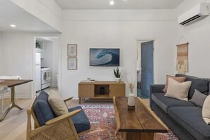 Una sala de estar moderna con un sofá, una mesa de centro de madera y un televisor montado en la pared.