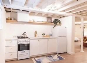 A kitchen with white cabinetry, a stove, and a refrigerator.