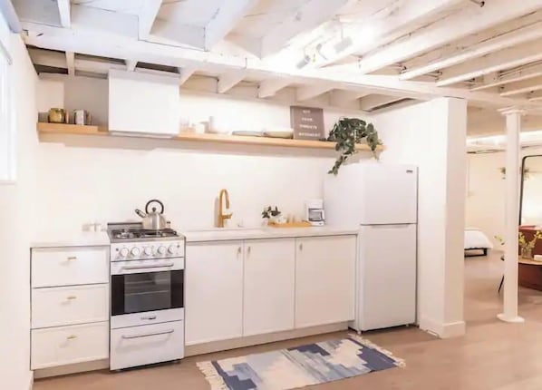 A kitchen with white cabinetry, a stove, and a refrigerator.