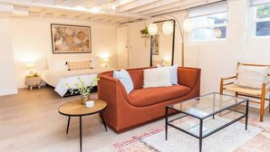 A modern living room with a sofa, coffee table, and a bed with a white duvet.