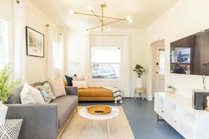 Un salon moderne avec un canapé, une table basse, un téléviseur et une grande fenêtre.