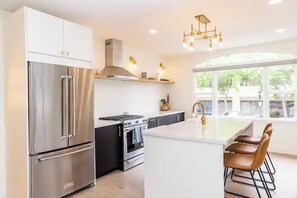 A modern kitchen with stainless steel appliances, a central island, and a large window providing natural light.