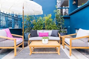 A patio with a wooden table, two sofas, and a white umbrella.