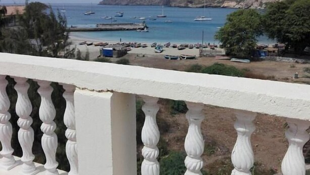 A coastal view with boats docked at a pier, a sandy beach, and a mountainous backdrop. - Tarrafal Residence (Tarrafal)