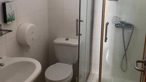 A bathroom with a glass-enclosed shower, a toilet, and a sink. - Tarrafal Residence (Tarrafal)