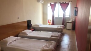 A hotel room with three single beds, a desk with a chair, a small kitchenette, and a window with curtains. - Tarrafal Residence (Tarrafal)