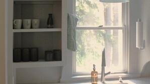 A kitchen with white cabinets, a Bosch dishwasher, a window with a view of trees, and a hanging pendant light. - Corkscrew Cape - Family Friendly Upstate NY Escape (Barryville)