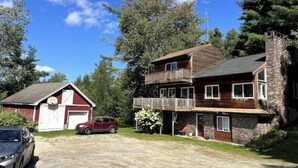A two-story house with a wooden deck and a garage. - Green Mountain Access:

 (Rutland)