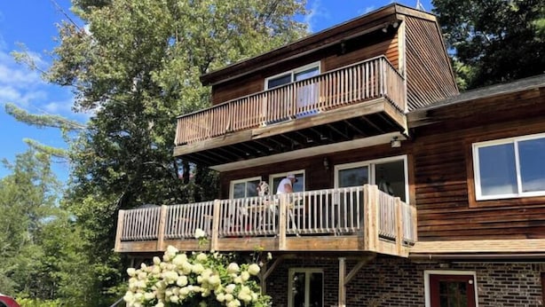 A two-story wooden house with a balcony, a brick lower level, and a red door. - Green Mountain Access:

 (Rutland)
