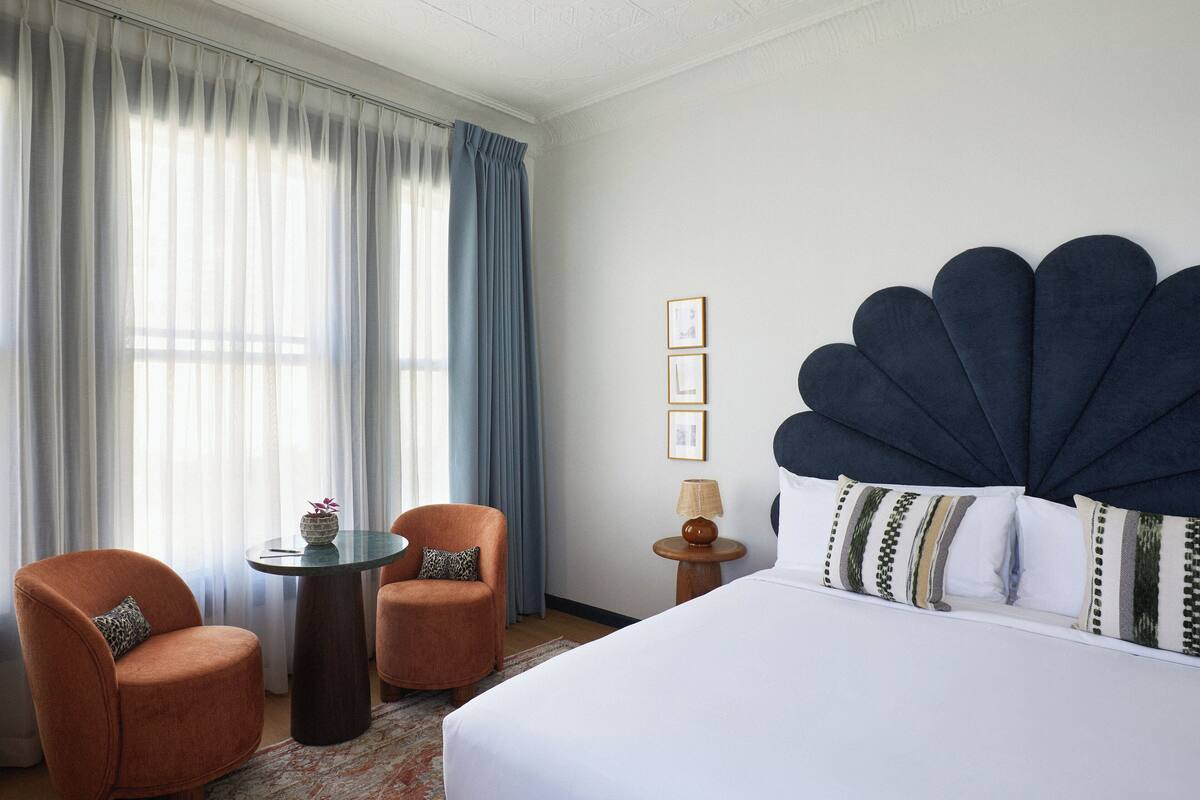 A hotel room with a large bed, two armchairs, a small table, and a lamp.