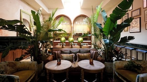 Un salon confortable, doté de meubles en bois, d’une cheminée et d’une végétation tropicale luxuriante.
