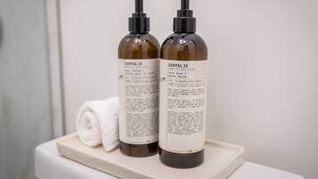 Two bottles of Santal 33 body lotion and hand soap on a beige tray.